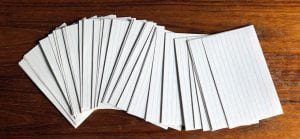 a pile of blank lined notecards is spread out across a wood table